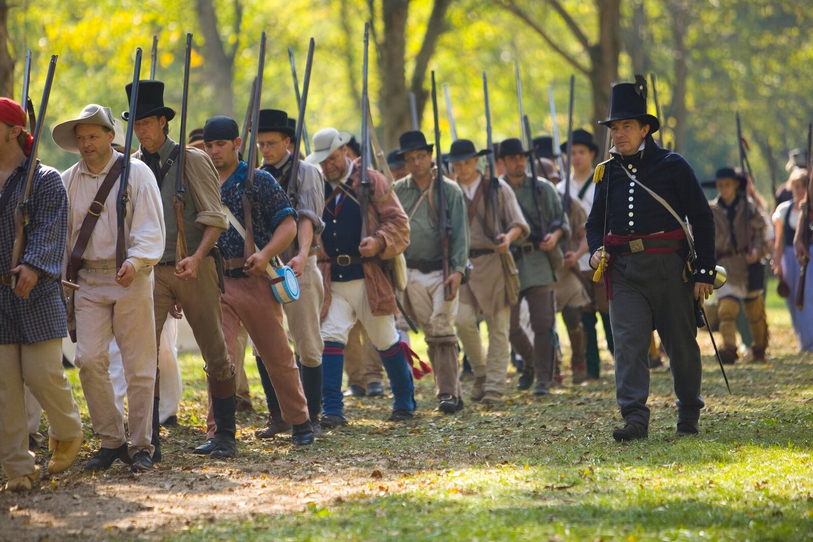 Reenactors in period uniforms march with muskets at the Mississinewa 1812 living history event in Grant County, Indiana